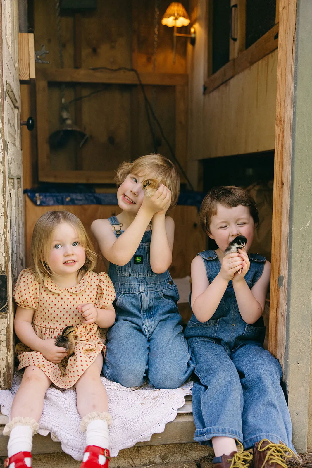 Three children laughing in a barn doorway